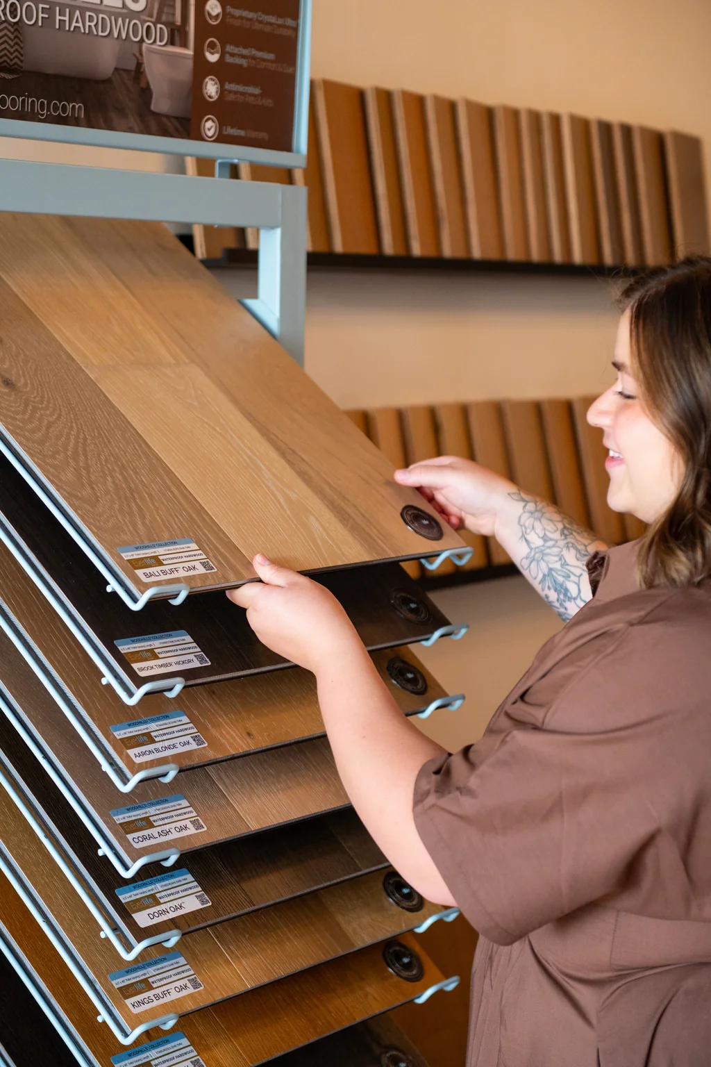 Customer browsing hardwood sample boards on the display rack at the Danny Boy Flooring design studio in Creedmoor